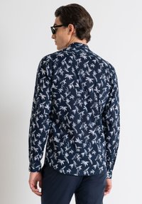 Maglietta a maniche lunghe blu navy con motivo foglia bianca, polsini con bottone e orlo curvato. Tessuto morbido con vestibilità regolare.