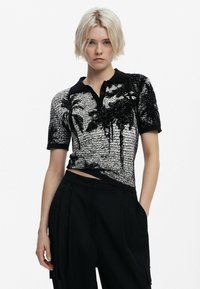 Zwart-wit polo shirt met korte mouwen, gekenmerkt door een geweven patroon en palmbomen graphics. Het heeft een zwarte kraag en knoopsluiting.