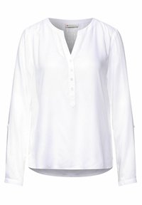 Blusa bianca a maniche lunghe con scollo a V e patta con bottoni. Caratterizzata da maniche arricciate e orlo arrotondato. Tessuto morbido e leggero.