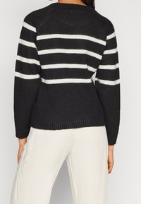 Maglione a righe bianco e nero in maglia con vestibilità rilassata, orlo a coste e maniche a raglan, caratterizzato da una delicata texture e righe a contrasto.
