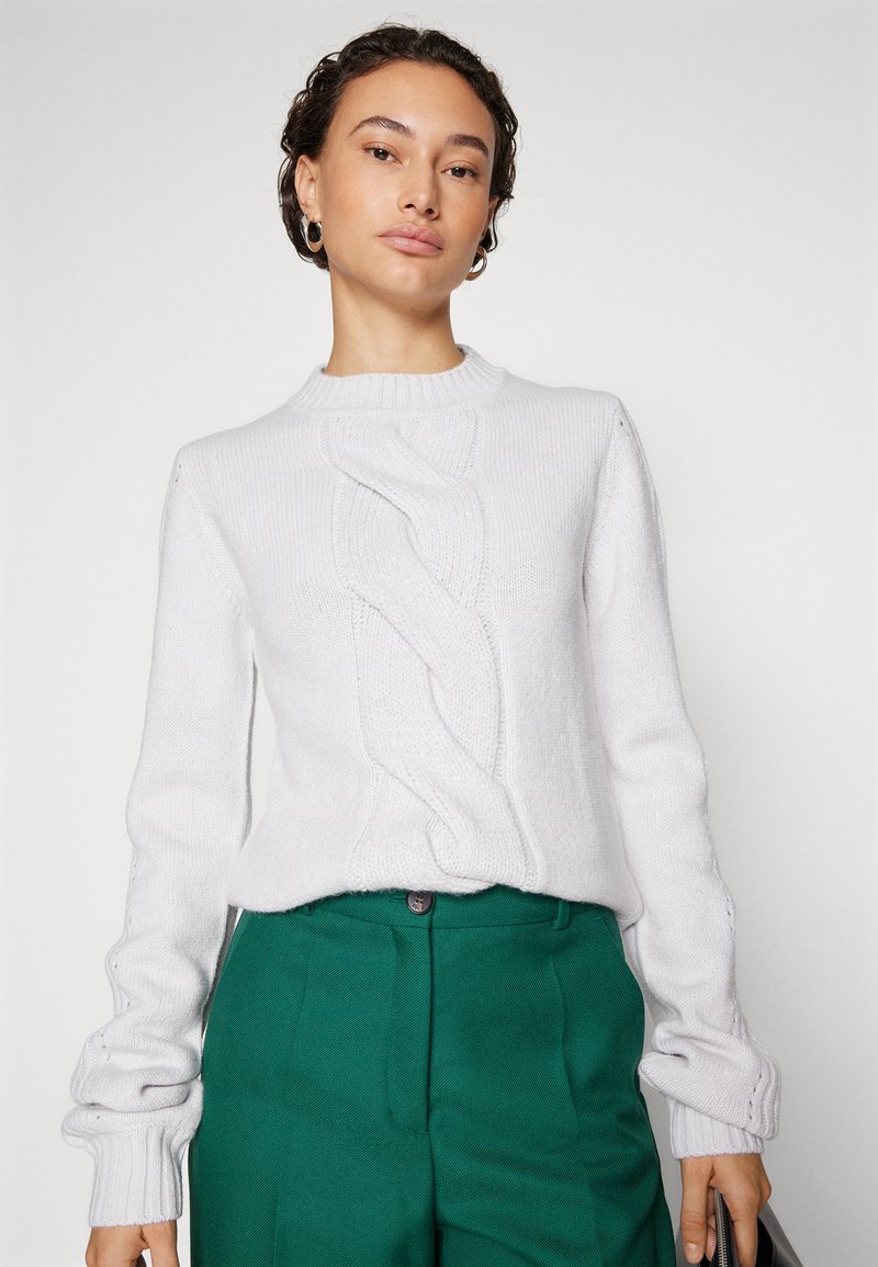 Pullover grigio chiaro lavorato a maglia con un design a treccia intrecciata, colletto a coste e maniche lunghe, abbinato a pantaloni verdi su misura.