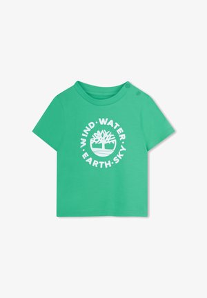 Groen T-shirt met korte mouwen van katoen, met een rond logodesign met de woorden "WIND • WATER • EARTH • SKY" in wit. Twee drukknoopsluitingen op de schouder.