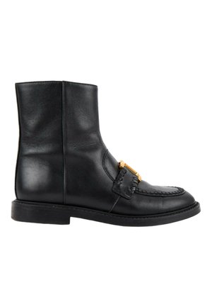 Bottine en cuir noir avec un petit talon, couture style mocassin et une boucle dorée décorative à l'avant.