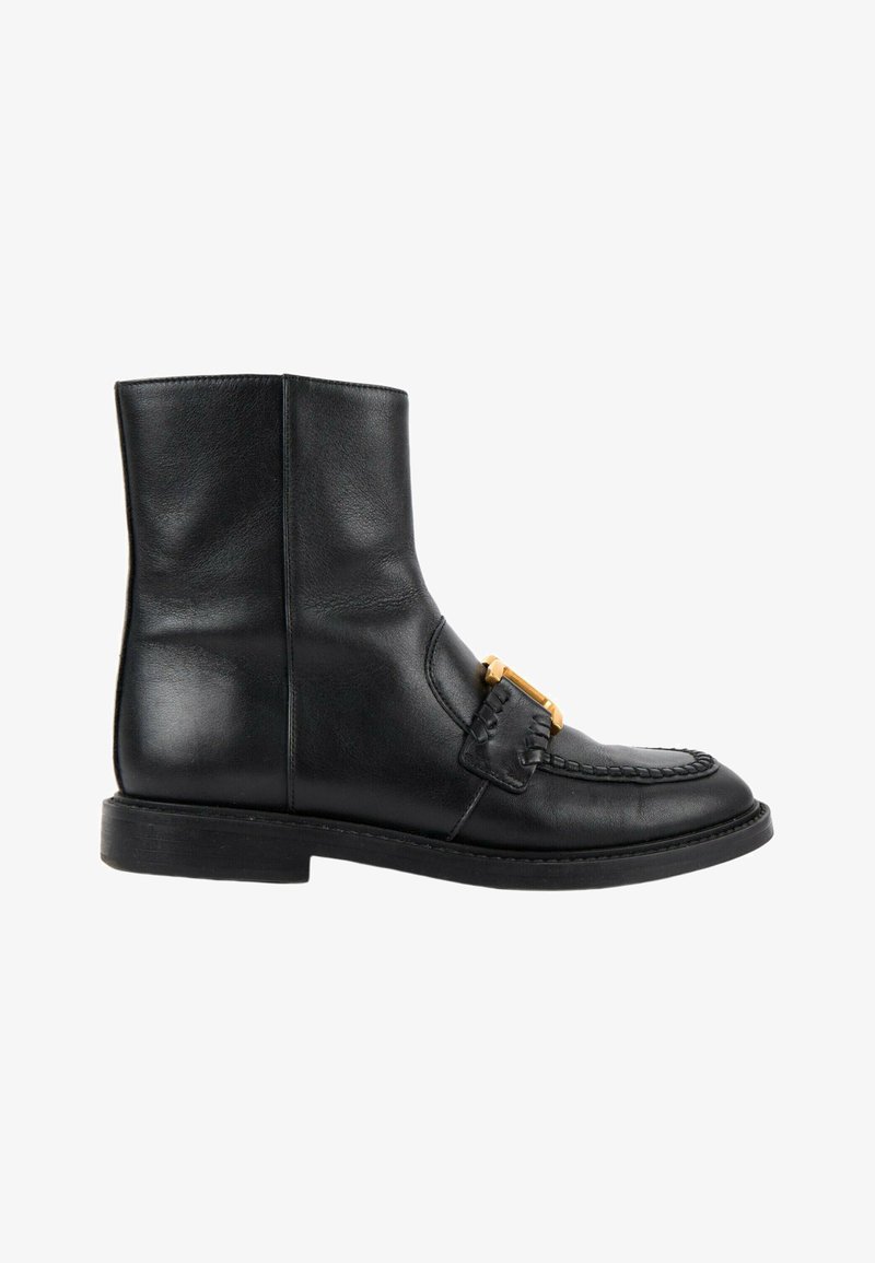 Bottine en cuir noir avec un petit talon, couture style mocassin et une boucle dorée décorative à l'avant.