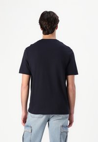Tamsiai mėlynas trumpas rankovė t-shirt, apvalios iškirptės dizainas, pagamintas iš minkštos medžiagos. Paprasta nugarėlė be matomų logotipų ar raštų, laisvas kirpimas.