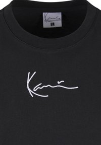 Mustast puuvillast T-särk, millel on ümar kaelus ja valge tikitud allkirjaga logo ees, siledal kangapinnal.