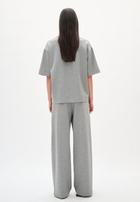Pantaloni corti grigi con vestibilità ampia e gambe larghe, abbinati a una maglia oversize a maniche corte dello stesso colore. Tessuto morbido.
