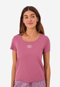 Kurzärmliges T-Shirt mit Rundhalsausschnitt aus leichtem, rosa Baumwollstoff mit gerippter Struktur; auf der Front ist "SUMMER NIGHTS" in Weiß gestickt.