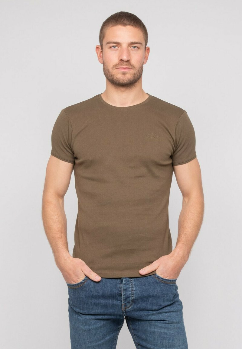 T-shirt à manches courtes vert olive en coton, avec un col rond et une silhouette ajustée, associé à un jean bleu.