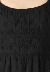 Μαύρο φόρεμα από ύφασμα με μοτίβα floral κεντημένα, συγκεντρωμένος λαιμός και σταφιδωτή μέση για υφασματική υφή. Λείο, ελαφρύ υλικό.