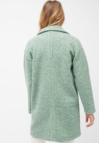 Cappotto verde strutturato con colletto, maniche lunghe e silhouette leggermente oversize, realizzato in materiale morbido e soffice.