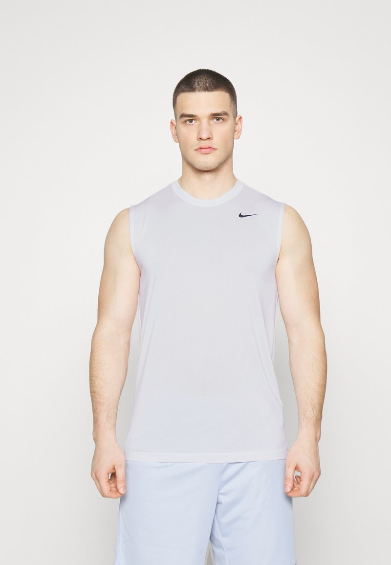 Bezrękawnik w jasnoszarym kolorze od Nike, wykonany z materiału sportowego, z okrągłym dekoltem, posiadający małe czarne logo po lewej stronie na górze.