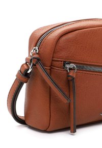 Brun læder crossbody taske med en struktureret form, sølv lynlås og kontrastfarvede mørke remme. Har en glat overflade og minimalistisk design.