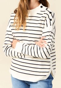 White striped sweater with navy and beige lines, featuring button accents on the shoulder and side slits. Soft knit texture.