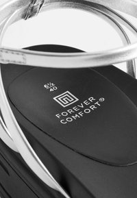 Sidabriniai sandalai su juodu paminkštintu padu, kuriuose išsiuvinėtas "FOREVER COMFORT" logotipas ir dydžio informacija balta spalva.