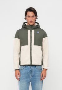 Grønn og kremfarget zip-up jakke med hette, med fleece tekstur og fargeblokkdesign. Inkluderer logo på brystet og sidelommer.