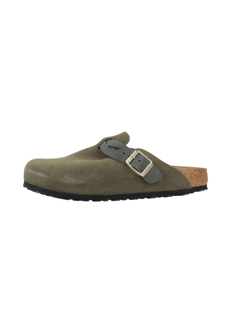 Clog en suède vert olive, à enfiler, avec une sangle ajustable noire et un semelle en liège, présentée en profil latéral sur fond blanc.