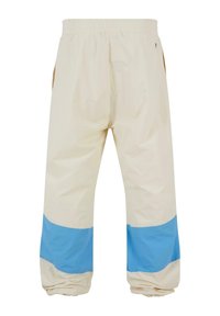 Pantaloni ușori bej cu talie elastică și două buzunare laterale. Prezintă accente de culoare albastră la manșete și o textură netedă.