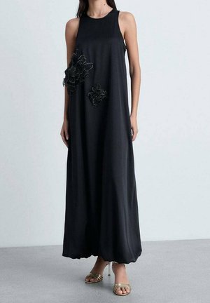 Zwart mouwloos maxi-jurk met bloemenborduurdetails aan de linkerkant. Gemaakt van een gladde stof, met een losse pasvorm en een brede zoom.