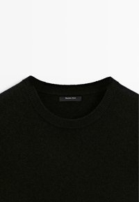 Pull noir à col rond avec col côtelé, vu de dessus, portant une étiquette Massimo Dutti à l'intérieur du col. Aucun motif visible.