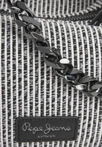 Borsa in tessuto a righe bianche e nere con superficie texture, dotata di tracolla in catena nera lucida e una toppa con logo nera.
