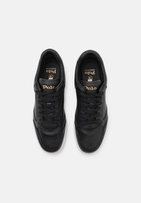 Svarta läder sneakers med slät finish, perforerad tå, platta snören och vit gummisula. Gyllene logotyp på tungan.