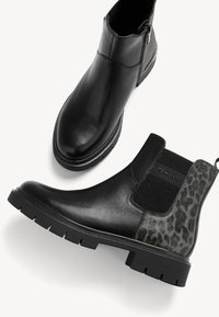 Botas de cuero negras hasta el tobillo con paneles laterales elásticos y acentos de estampado animal texturizado. Suelas de goma gruesa ofrecen tracción y durabilidad.