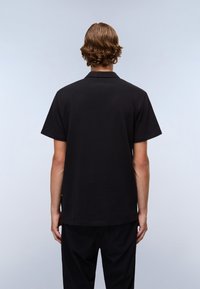 Svart kortermet polo skjorte med rett snitt, laget av glatt bomull. Har klassisk krage og minimal sømdetalj i kanten.