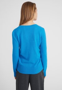 Pullover blu brillante con scollo rotondo e fondo a costine, realizzato in materiale morbido. Caratterizzato da maniche lunghe e un design semplice e minimalista.