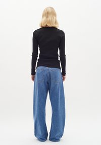 Maglietta nera aderente a maniche lunghe abbinata a un paio di jeans in denim azzurro chiaro oversize, con tasche posteriori e una silhouette rilassata.