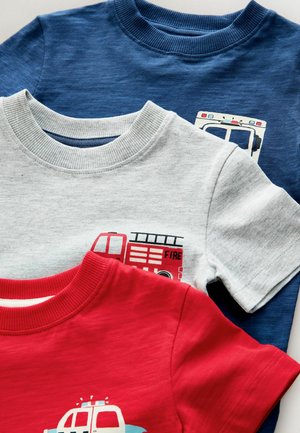 Drei gefaltete Kinder-T-Shirts in Rot, Grau und Blau mit Feuerwehr- und Krankenwagen-Motiven auf der Brust.