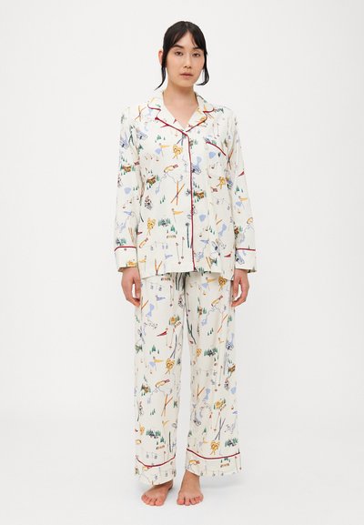 Conjunto de pijama de dos piezas en tejido color crema con un estampado colorido de naturaleza y actividades, con ribete rojo en el cuello y los puños.