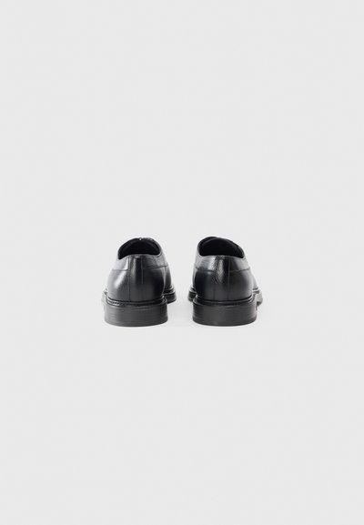 Black leather shoes with a smooth texture, rounded toe, and low heel. Features minimalistic design with no visible embellishments.