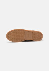 Semelle en caoutchouc marron avec une surface texturée et un logo imprimé ; bout rond et design simple et minimaliste.