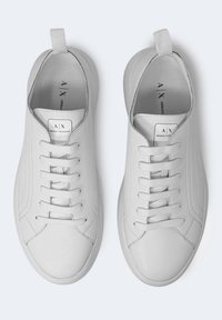 Paire de baskets basses en cuir blanc avec lacets blancs, languettes au talon et logo "A|X Armani Exchange" sur la languette et les semelles intérieures.