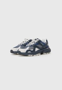 Sneakers z siateczkową cholewką w granatowo-białym kolorze, wyściełanym kołnierzem i grubą gumową podeszwą z teksturowanym wzorem oraz detalem z logo.
