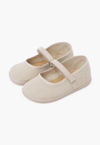 Zapatos Mary Jane de lona beige con puntera redonda y cierre de tiras de tela. Diseño ligero con una textura suave y suela flexible.