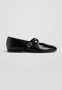 Ballerines noires en cuir lisse, avec un bout arrondi, des détails de bande croisées et un accent de boucle en argent sur le côté.
