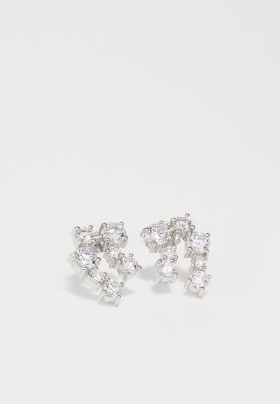 Boucles d'oreilles en argent présentant un design torsadé orné de multiples pierres précieuses transparentes de tailles variées, mettant en avant une finition haute brillance.