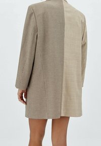 Brown geruite oversized blazer met een mix van kleine en grote ruitpatronen, voorzien van lange mouwen en een tailored fit.