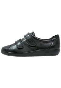 Scarpa in pelle nera con punta arrotondata, due cinturini in velcro regolabili e suola nera imbottita per il comfort. Texture liscia, design minimalista.