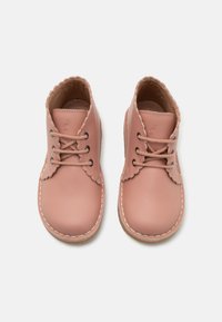 Zapatos de cuero rosa con cordones, con bordes en forma de ondas y costuras en contraste, presentan una punta redonda y un forro interior suave.