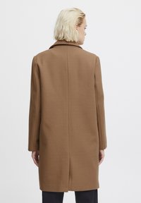 Cappotto in lana marrone con taglio dritto, design di lunghezza media, colletto a risvolto e maniche lunghe, con una cucitura centrale sul retro e hardware minimale.