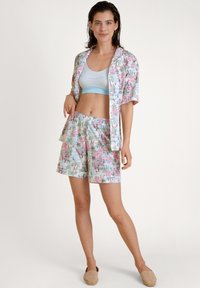 Camicia a maniche corte con motivo floreale e pantaloni corti in azzurro chiaro, caratterizzata da disegni rosa e verdi. Tessuto morbido, vestibilità rilassata e cintura elastica.