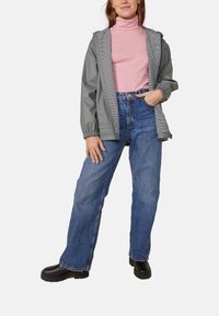 Gray waterproof jacket with striped lining, worn over a pink turtleneck, paired with blue wide-leg jeans and black boots.