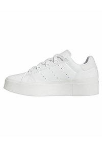 Vit sneaker med övre i slätt läder, rund tå och flata snören. Har en kraftig gummisula och små perforeringar för ventilation.