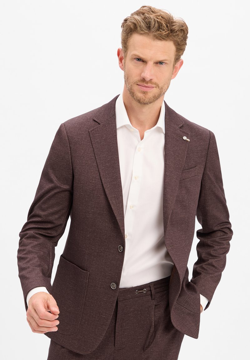 Burgunderfarbene Sakko aus strukturierter Stoff mit Revers, zwei Knöpfen und einer Tasche. Kombiniert mit einem weißen Dresshemd. Maßgeschneidertes Design.