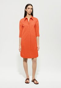 Oranges Baumwollhemdkleid mit Kragen, drei Viertel langen Ärmeln und gerader Form. Verfügt über eine partielle Knopfleiste und einen abgerundeten Saum.