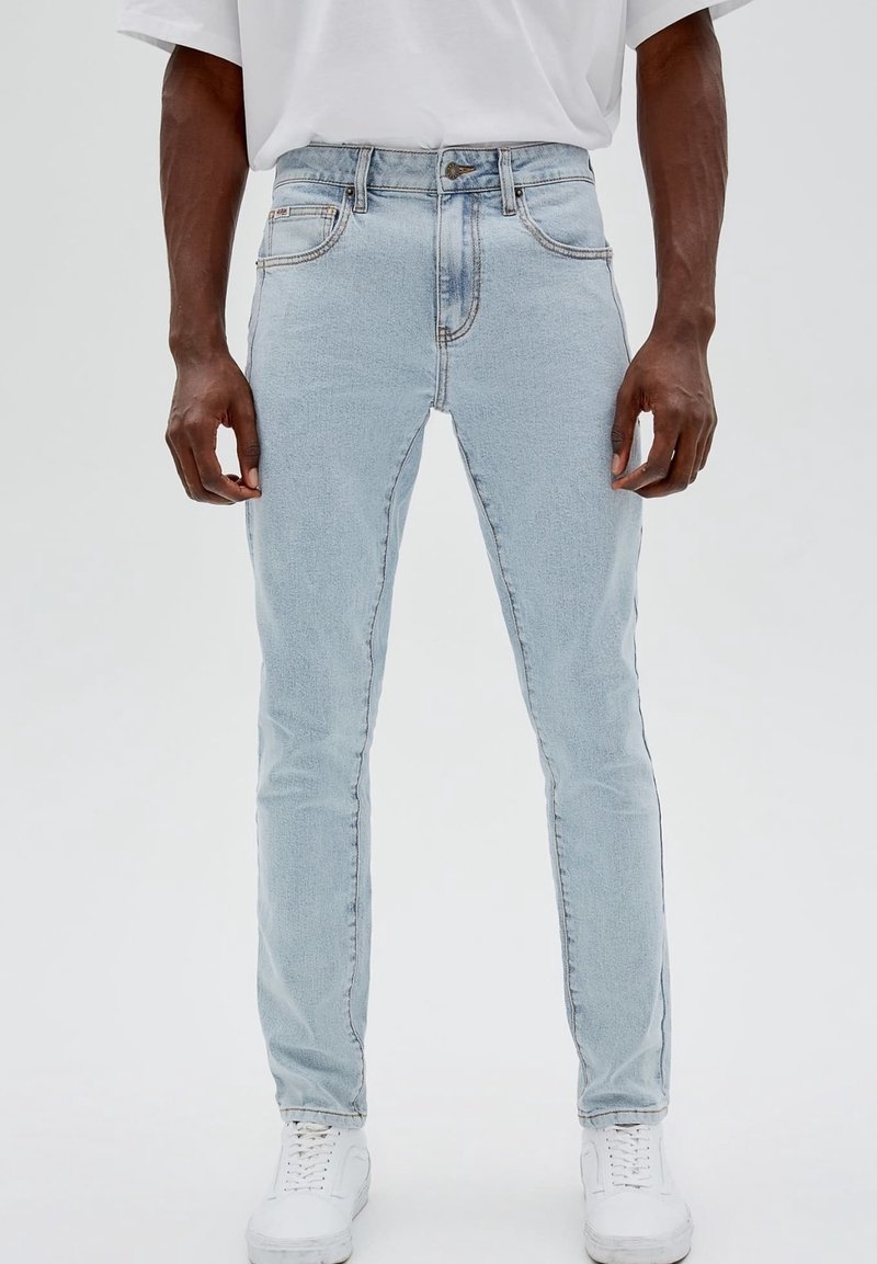 Ljust blå skinny jeans i denim, med hög midja, fem fickor, diskret sömnad och fransig fåll. I kombination med vita sneakers.