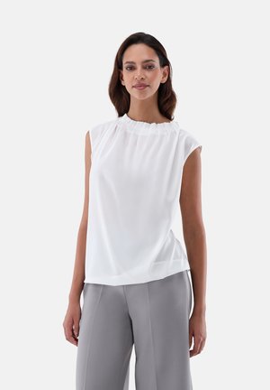 Blusa bianca senza maniche con collo plissettato, realizzata in tessuto leggero, abbinata a pantaloni larghi grigi. Texture morbida, design semplice.